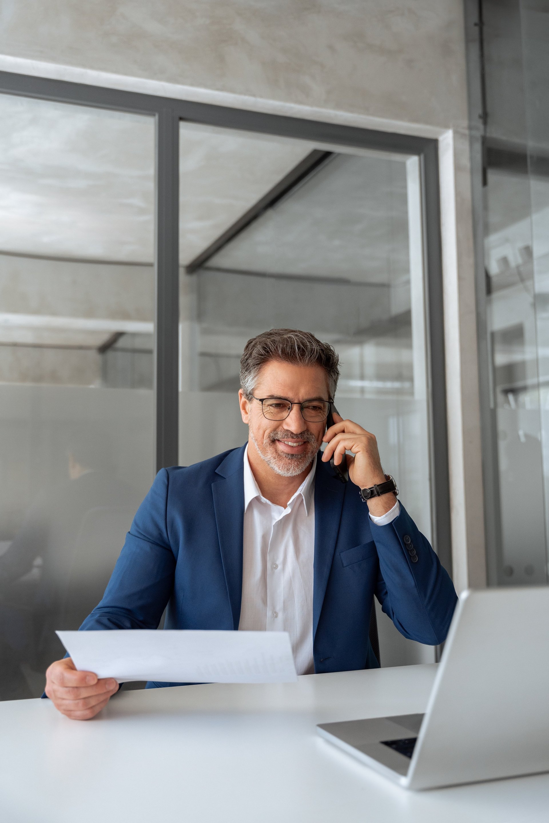 Mature businessman working on laptop at desk with financial data