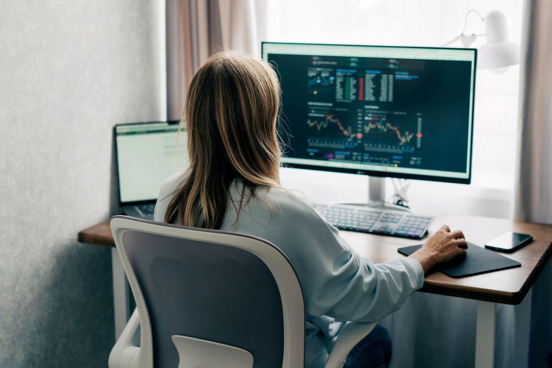 Woman analyzing investment charts at computer desk